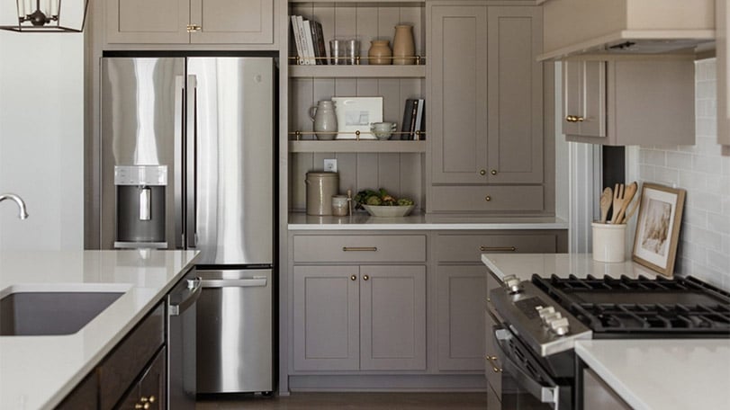 Modern kitchen with gray painted cabinets, stainless steel appliances, and quartz countertops