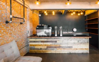 Modern industrial cafe interior with exposed brick wall, reclaimed wood bar, and dark walls in Annapolis MD