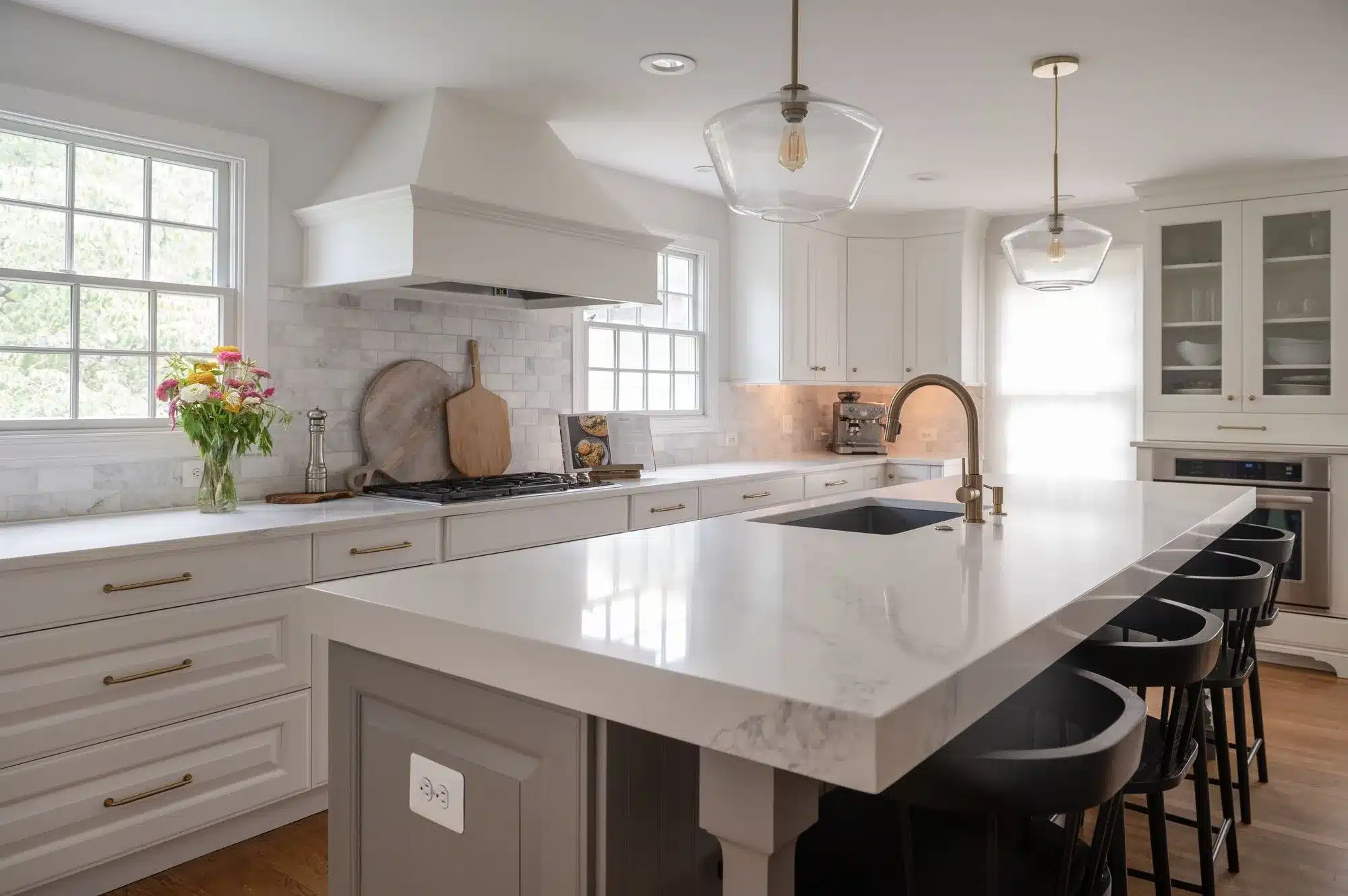 Modern white kitchen with large island, sleek cabinetry, and pendant lighting