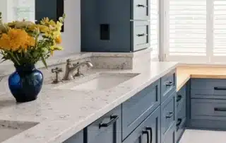 Blue painted cabinets with white quartz countertop and blue vase with yellow flowers