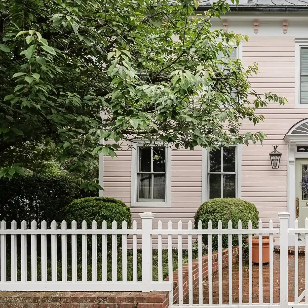 Light pink historic house exterior with white picket fence and manicured bushes in Annapolis MD