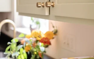 Freshly painted green upper kitchen cabinets with modern brass knobs