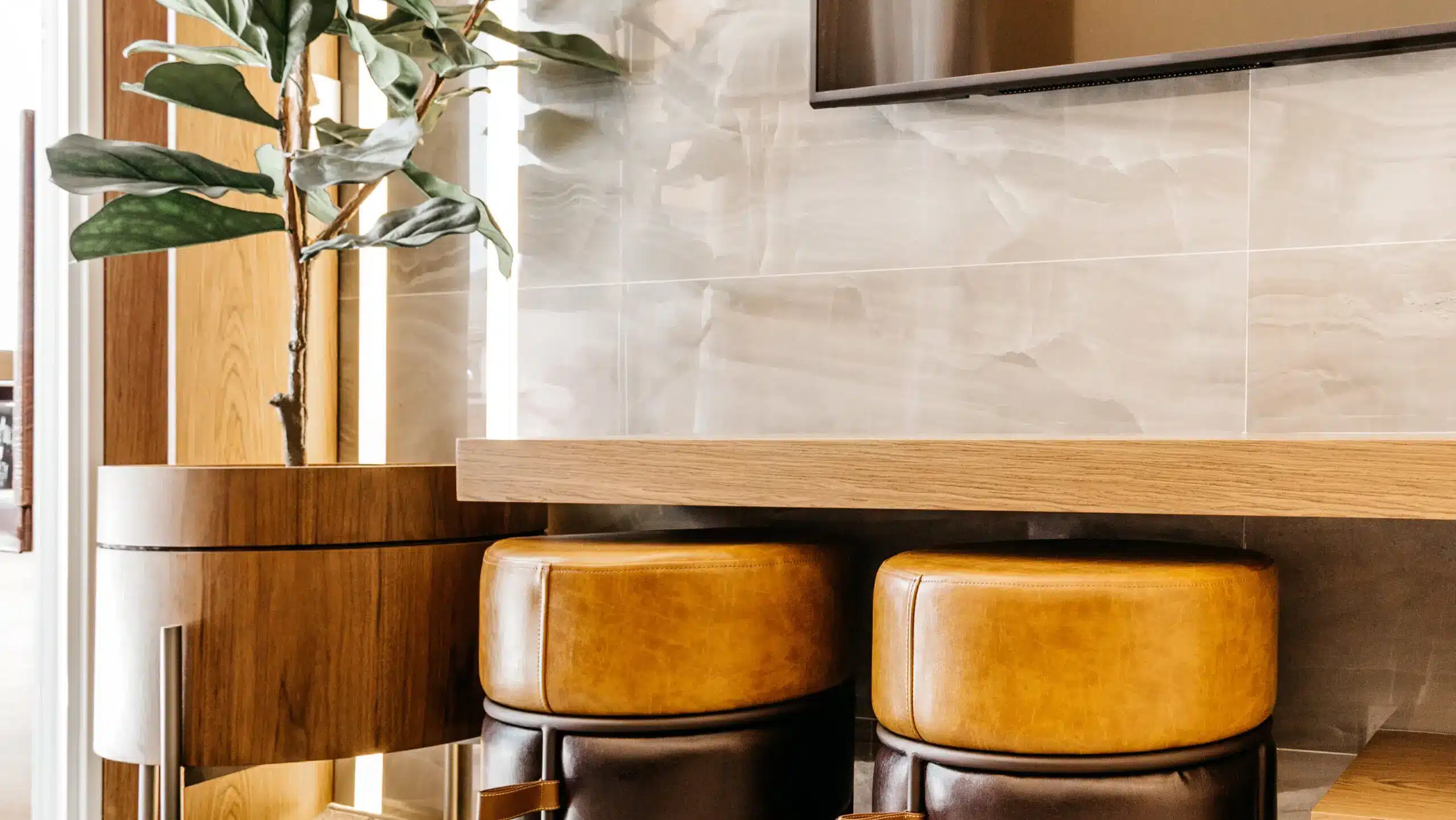 Modern living room interior featuring a tall potted plant and two yellow leather stools