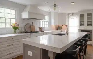 Modern white kitchen with refinished cabinets, large marble island, and black bar stools