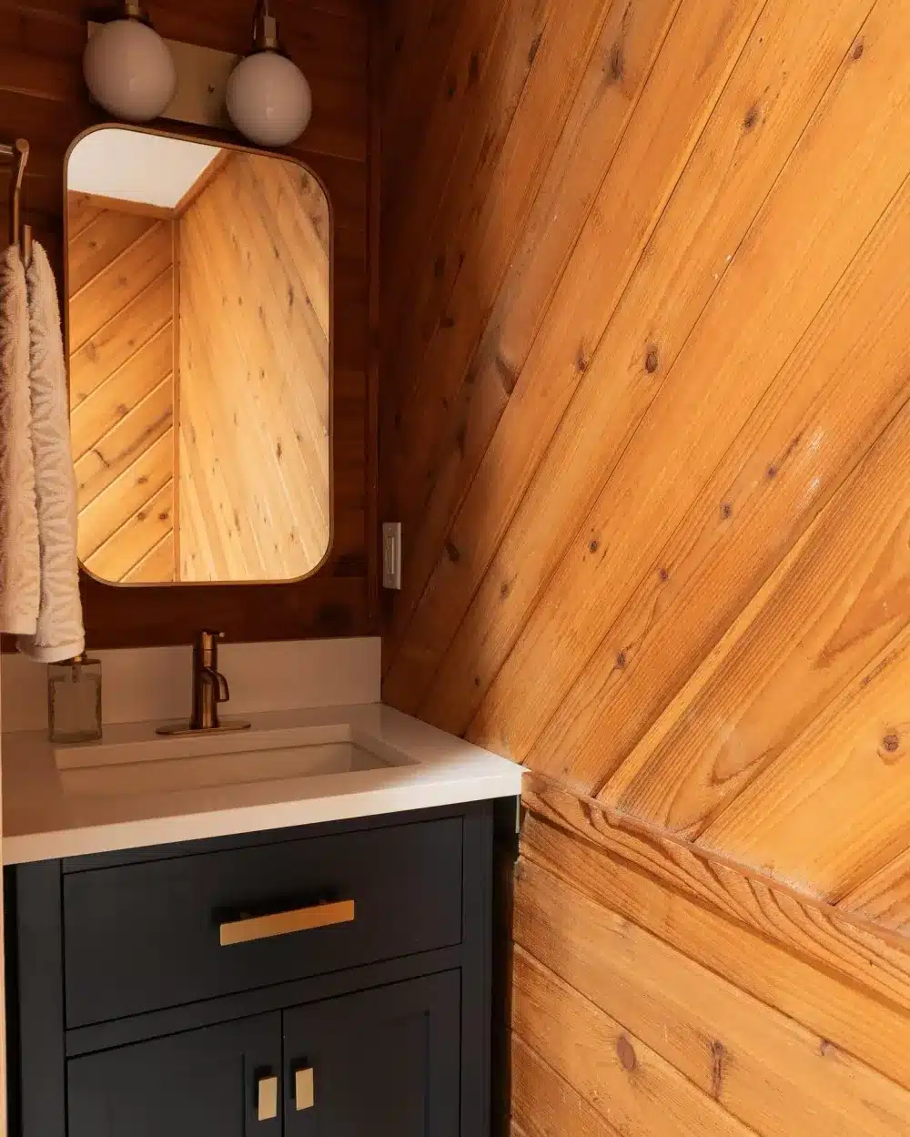 Dark blue vanity with white countertop and vertical wood panel walls