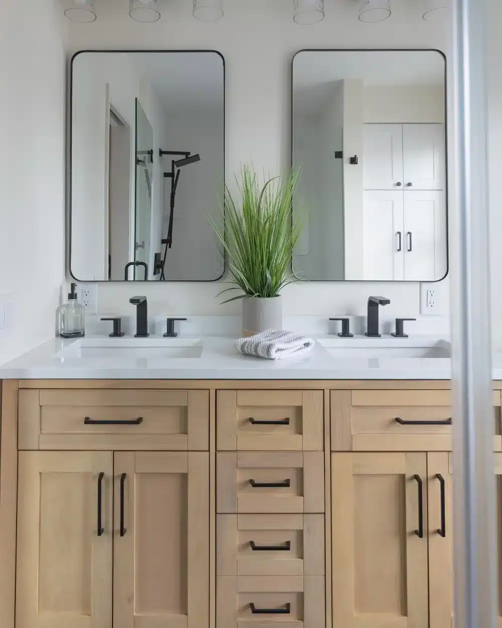 Light wood double vanity with black hardware and white countertops