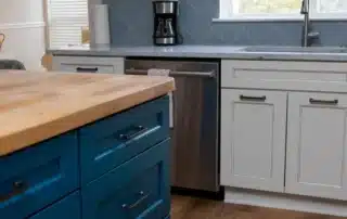 Two-tone kitchen cabinets with blue island and grey perimeter cabinets