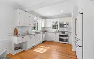 Bright white kitchen cabinets and subway tile backsplash with hardwood floors