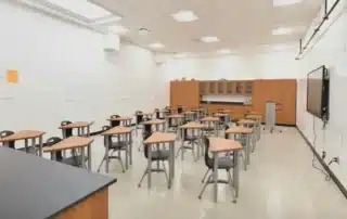 Empty modern school classroom with wooden desks and white walls