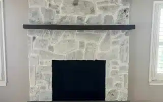 Light grey stone fireplace with dark wood mantel and hearth