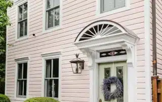 Pink two-story home with white trim, green front door, and lavender wreath