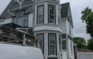 Exterior Painting Victorian House Annapolis Md Victorian style home with white siding, dark grey trim, and corner turret undergoing exterior painting in Annapolis MD