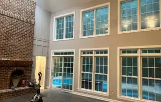 High ceiling living room with brick fireplace and large windows undergoing interior painting