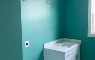 Interior Painting Teal Laundry Room Annapolis Md Teal painted walls in a laundry room with a white utility sink cabinet and wire shelving