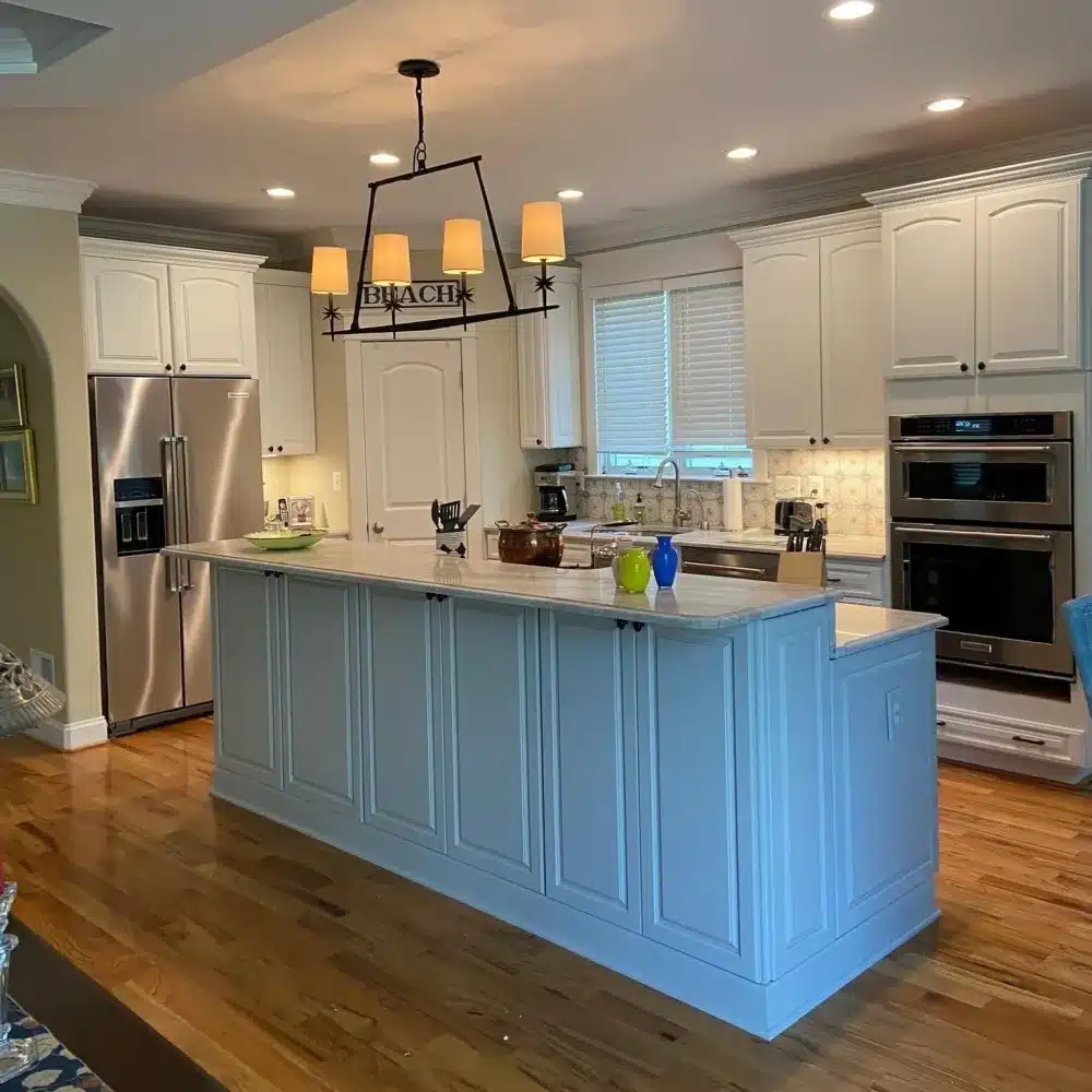 Light grey kitchen island and white cabinets with hardwood floors