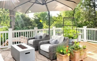 Cozy outdoor deck seating area with large patio umbrella, fire table, wicker armchairs, and potted plants in Annapolis MD