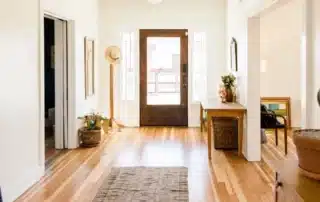 Bright residential foyer with hardwood floors, white trim, and dark wooden front door
