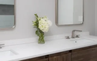Modern bathroom vanity featuring dark walnut wood cabinets, white quartz countertop, and chrome fixtures