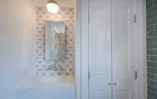 Modern residential bathroom sink area featuring patterned wallpaper and white double doors in Annapolis Md