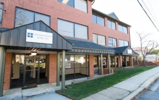 Red brick commercial office building with black metal awnings and glass doors in Annapolis Md