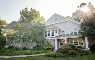 Large two-story residential home with grey siding and lush landscaping
