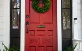 Vibrant red front door with black trim and white siding on a residential home