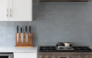 Modern kitchen with grey tile backsplash, stainless steel range, and white cabinets in Annapolis Md