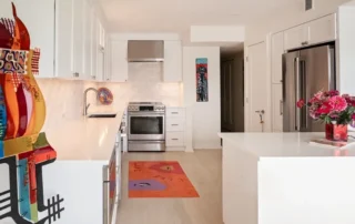 White kitchen with stainless steel appliances and vibrant art pieces