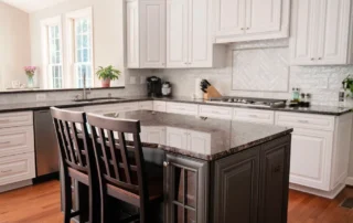 White kitchen cabinets and dark island with wooden barstools in Annapolis home