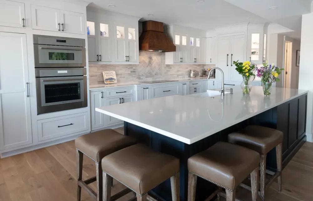 White kitchen island with quartz countertop and brown leather bar stools