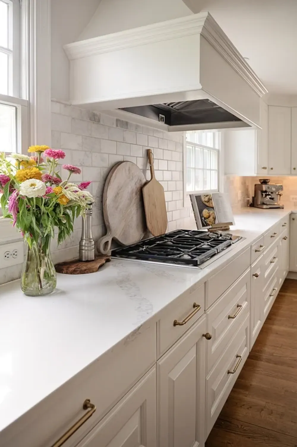 White kitchen counter with marble tile backsplash, range, and flowers
