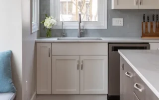 Modern kitchen with white quartz countertops, grey cabinets, and a built-in window seat