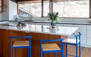 Wood kitchen island with white quartz countertop and blue metal stools