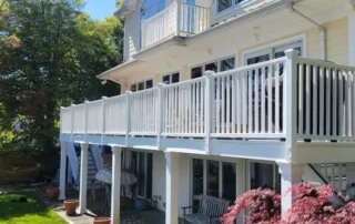 Yellow two-story home with white railings on a large elevated deck