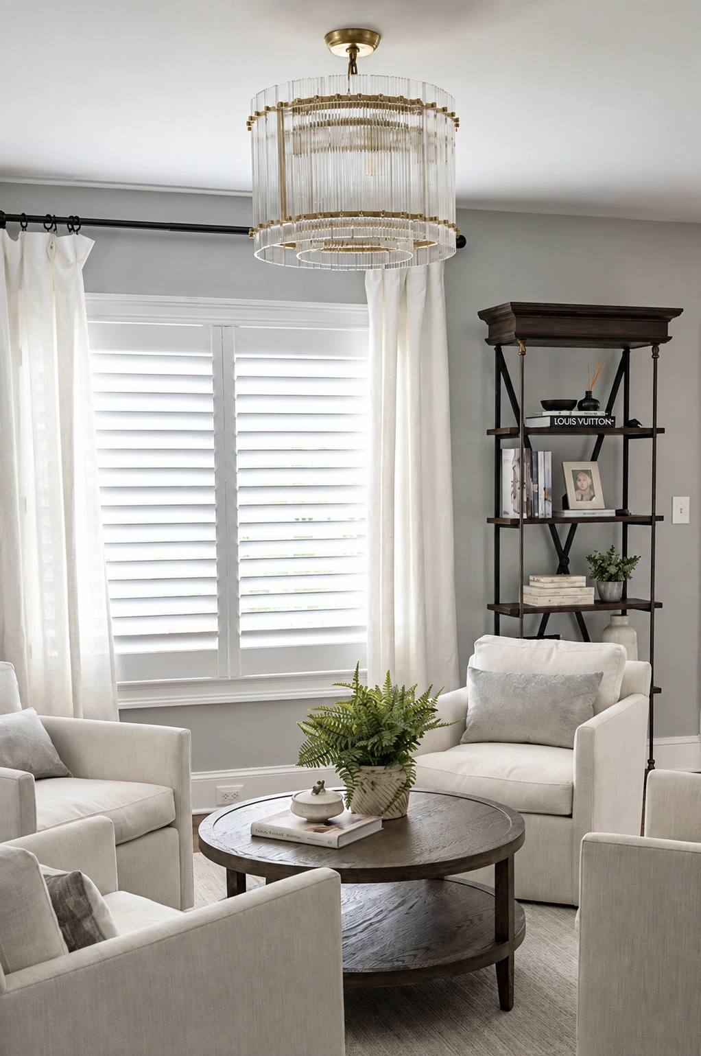 Bright sitting room with white seating, window shutters, and a decorative chandelier