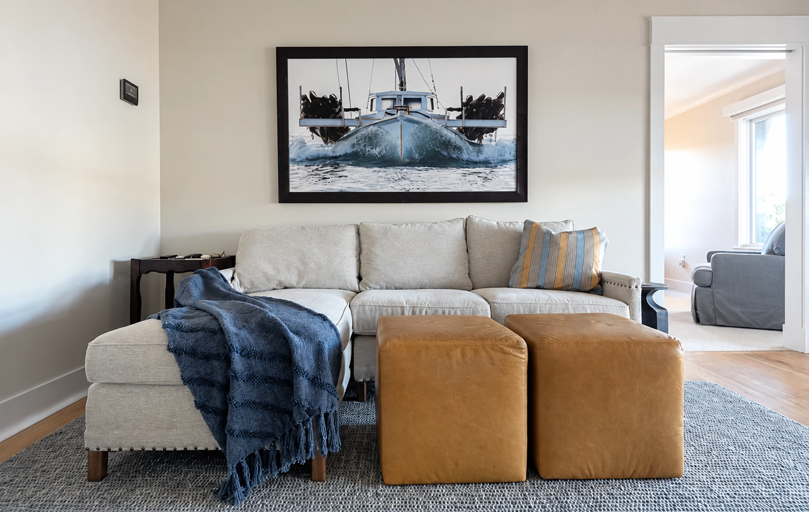 BlueStar_021 Living room with a light sectional sofa, blue throw, and caramel-colored ottomans