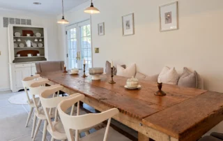 BlueStar_069 Dining room with a long wood table, white chairs, and pendant lighting