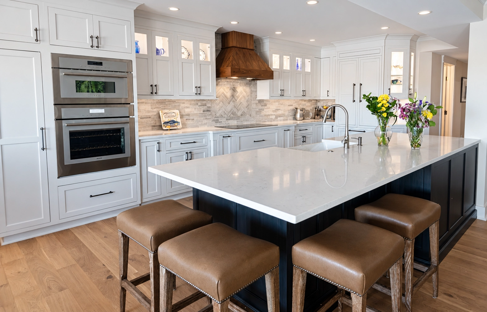 White shaker kitchen cabinets with a wood range hood and navy island