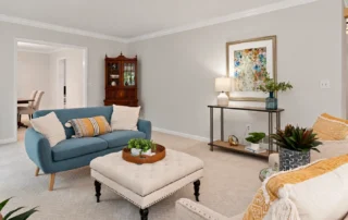 full-7 Living room with neutral walls, a blue sofa, and a white ottoman