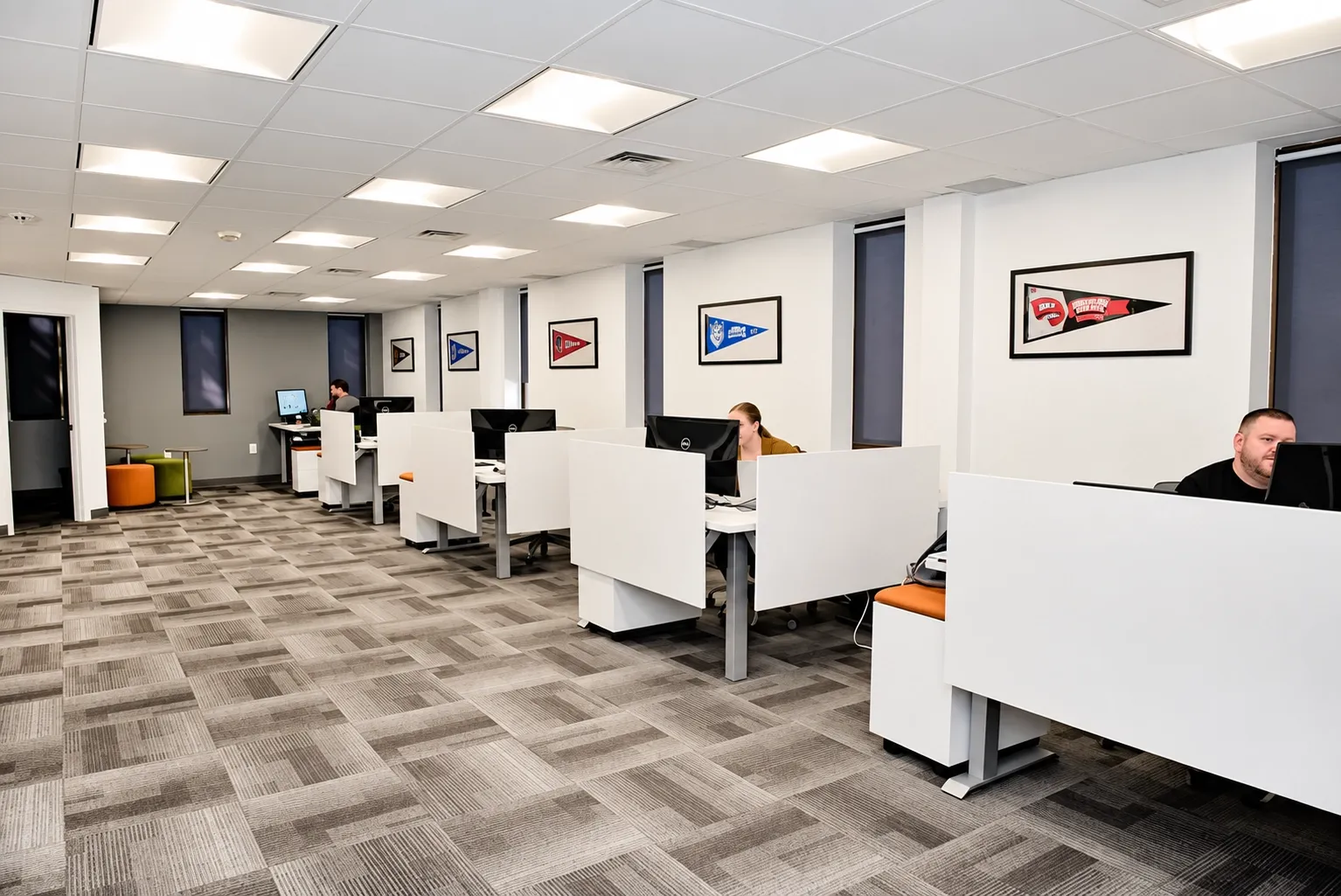 Open-plan office with white workstations and gray patterned carpet