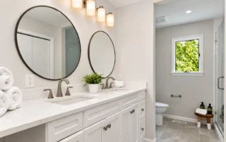 white-double-vanity-bathroom-round-mirrors White bathroom double vanity with round mirrors and wall lights