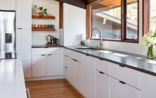 white-flat-panel-cabinets-black-countertops White flat-panel kitchen cabinets with black countertops and wood-framed windows